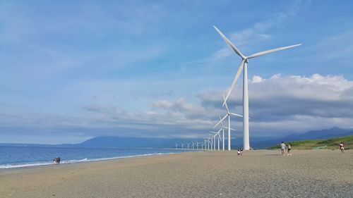 Wind turbines on beach against sky