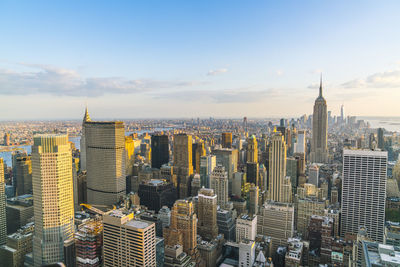 Aerial view of buildings in city against cloudy sky