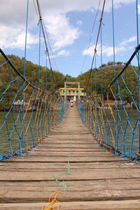 Footbridge hanging on suspension bridge against sky