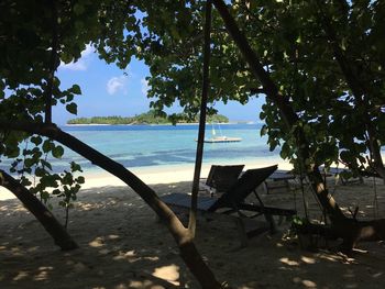 Empty chair on beach against sky