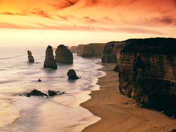 Rocks on beach against sky during sunset