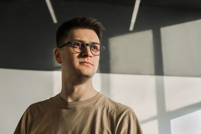 Portrait of young man standing against wall