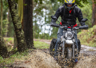 Man riding his scrambler type motorcycle through forrest