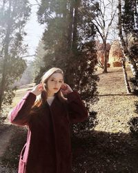 Young woman looking away while standing against trees