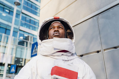 Male astronaut looking away while exploring city