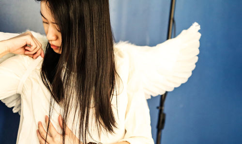 Side view of young woman standing against white wall