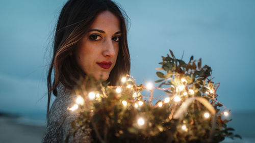 Sweet girl squeezes to herself bouquet of flowers with lights