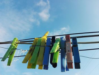 Low angle view of clothespins hanging on clothesline against sky