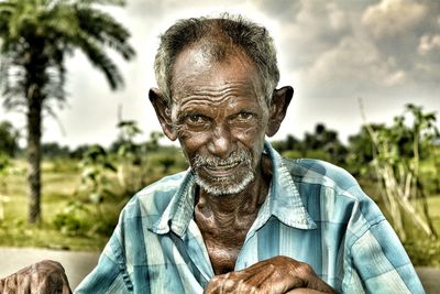 Portrait of senior man on field against sky