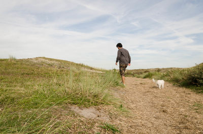 Rear view of man with horse standing on field