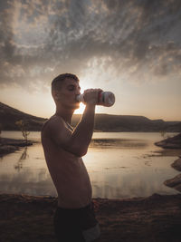 Man standing on beach against sky during sunset