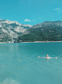 Carefree man swimming in sea against mountains