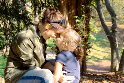 Midsection of women sitting on tree