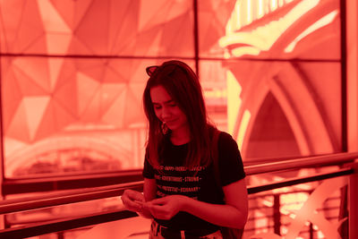 Smiling young woman packing marijuana joint while standing by railing 