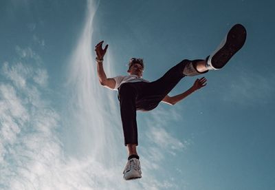 Low angle view of man with arms raised against sky