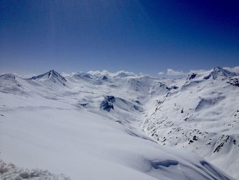 Scenic view of snowcapped mountains against clear blue sky