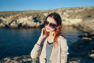 Portrait of young woman wearing sunglasses standing outdoors