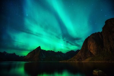 Scenic view of lake and mountains against aurora borealis at night