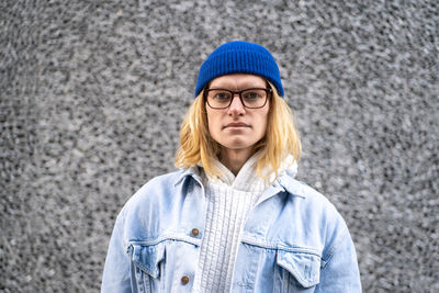 Portrait of young woman standing against wall