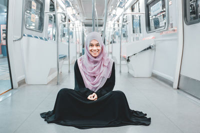 Portrait of smiling young woman wearing religious dress while sitting in train