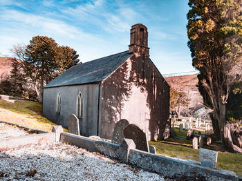 Old chapel by trees against sky