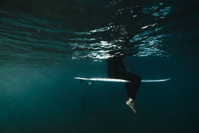 Underwater view of a surfer sitting on his board