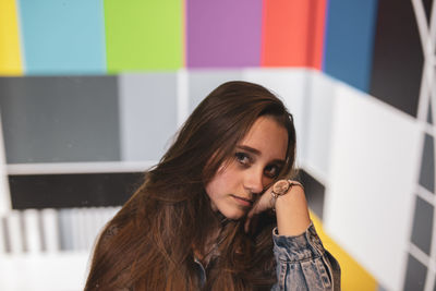 Portrait of young woman against multi colored wall
