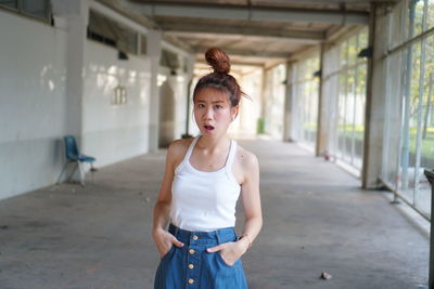 Portrait of a young woman standing against wall