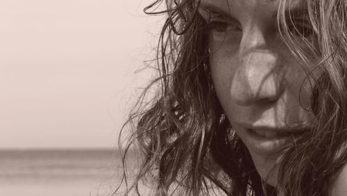 Close-up of young woman against sea and sky