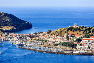 Aerial view of townscape by sea against sky