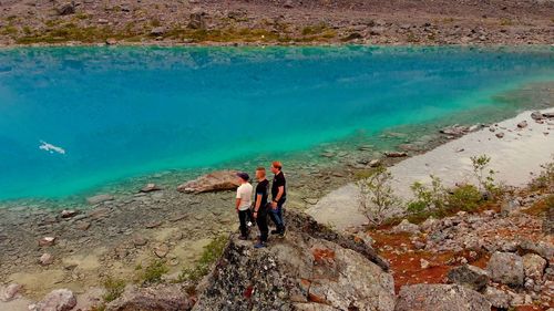 High angle view of friends standing on rock at shore