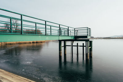 Railing by lake against clear sky