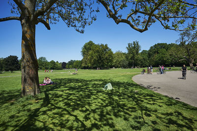 People relaxing in park against sky