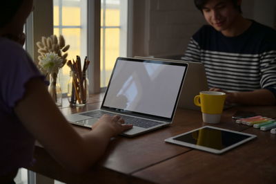 Midsection of man using mobile phone while sitting on table