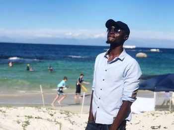 Mid adult man standing at beach against blue sky during sunny day