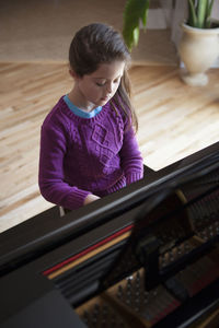 High angle view of girl playing piano at home