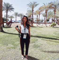 Portrait of smiling young woman standing against trees