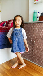 Cute lovely attractive cheerful cheery straight-haired little girl wearing jumpsuit jeans skirt.