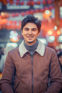 Portrait of smiling man standing on street at night