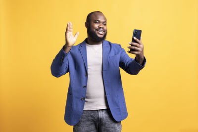 Young man using mobile phone against blue background