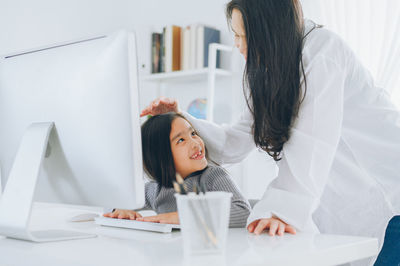 Young woman using phone while sitting on table