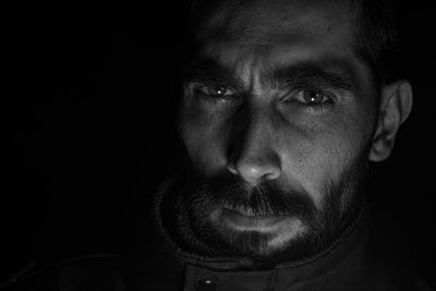 Close-up portrait of man against black background