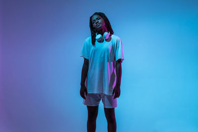 Full length of young woman standing against blue background