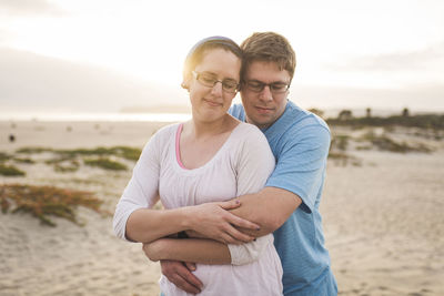 Man embracing woman while standing at beach