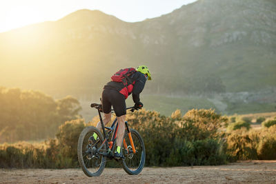 Rear view of man riding bicycle on mountain