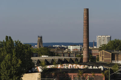 Smoke stack in city against sky