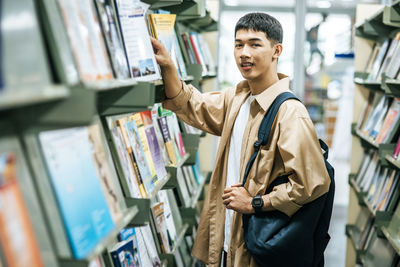 Side view of young man reading book