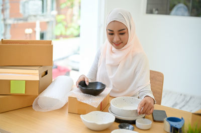 Young businesswoman in hijab packing parcels