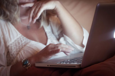 Midsection of woman using laptop at home