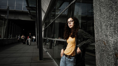 Thoughtful young woman standing outside building